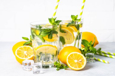 Limonata bardakta beyaz masada taze limon ve nane ile. Soğuk yaz içeceği.