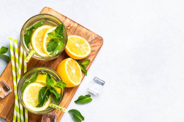 Limonata bardakta beyaz masada taze limon ve nane ile. Soğuk yaz içkisi üst görünümü.