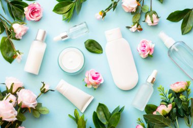 Mavi arka planda doğal kozmetik ürünler. Krema, serum, yeşil yapraklı ve çiçekli tonik. Cilt bakımı kavramı.