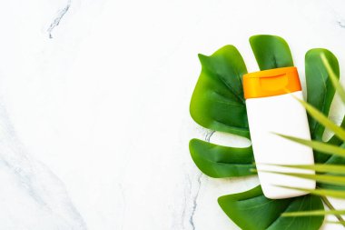 Beyaz arka planda palmiye yapraklı güneş kremi ürünleri. Güneş koruması. Metin için alanı olan düz resim.