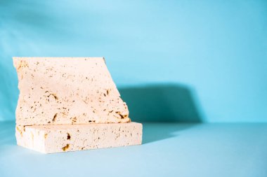 Travertine podyumu mavi arka planda kozmetik ürünler sunumu için. Palmiye yaprakları gölge.