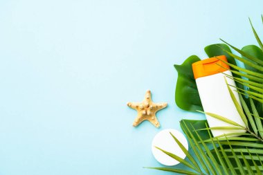 Mavi arka planda palmiye yapraklı güneş kremi ürünleri. Güneş koruması. Metin için alanı olan düz resim.