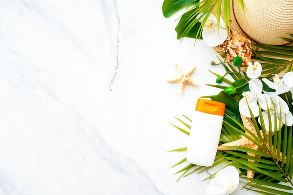 Summer holidays flat lay background. Sun screen products with palm leaves and shells on white. Flat lay with copy space.