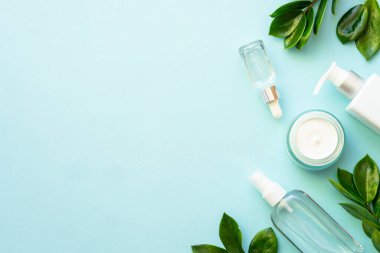 Doğal kozmetik ürünleri mavinin üzerine saçılmıştı. Yeşil yapraklı krema ve serum..