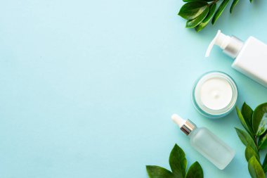 Doğal kozmetik ürünleri mavinin üzerine saçılmıştı. Yeşil yapraklı krema, sabun ve serum..