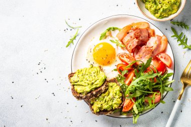 Fener, yumurta, avokadolu tost ve taze salata. Sağlıklı yiyecekler, paleo diyeti. Üst manzara beyaz mutfak masasında..