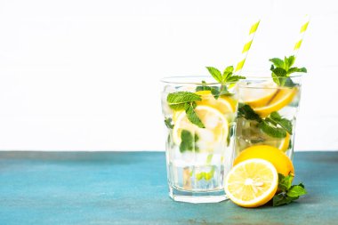 Limonata bardakta beyaz masada taze limon ve nane ile. Soğuk yaz içeceği.