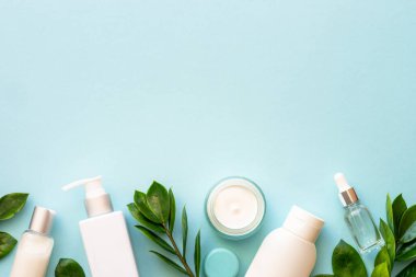 Doğal kozmetik ürünleri. Krema, serum, yeşil yapraklı tonik. Mavi arka planda düz uzandı.