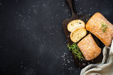 Siyah arka planda tahtadan yapılmış İtalyan Ciabatta ekmeği. Kopyalama alanı olan üst görünüm.