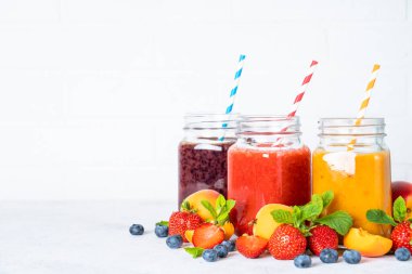 Beyaz arka planda taze meyve ve böğürtlenli meyve püresi. Kavanozda meyve püresi.