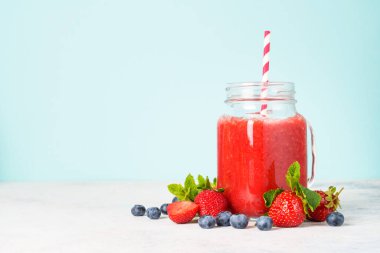 Mavi arka planda taze böğürtlenli çilekli smoothie.