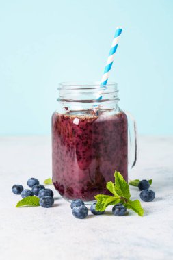 Mavi arka planda taze böğürtlenli cam kavanozda yabanmersini püresi..