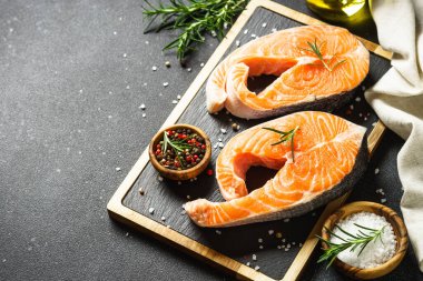 Somon balığı taze somon bifteği siyah arka planda kesme tahtasında. Kopyalama alanı olan üst görünüm.