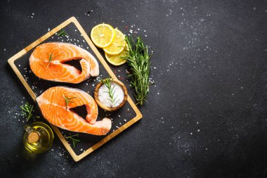 Baharatlı somon balığı. Siyah arka planda taze somon bifteği. Kopyalama alanı olan üst görünüm.