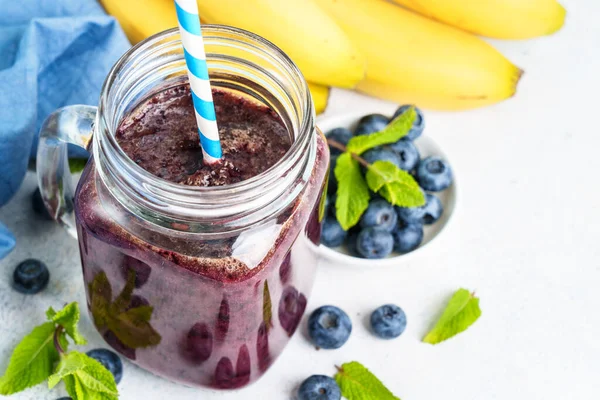 stock image Blueberry banana smoothie in glass jar at blue background.