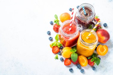Beyaz arka planda taze meyve ve böğürtlenli meyve püresi. Ev yapımı sağlıklı içecek..
