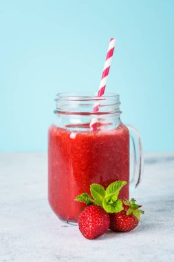 Mavi arka planda taze böğürtlenli çilekli smoothie.