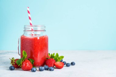 Mavi arka planda taze böğürtlenli çilekli smoothie.