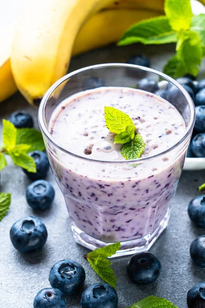 Stock image Blueberry banana smoothie or milkshake with fresh berries on stone table.