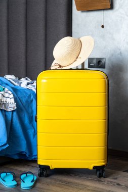Yatak odasında içinde bez ve şapka olan bavul. Seyahat konsepti, bavullar.
