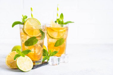 Buzlu çay. Limonlu, limonlu, naneli ve buzlu siyah çay. Soğuk limonata, yaz içkisi, beyaz arka plan..