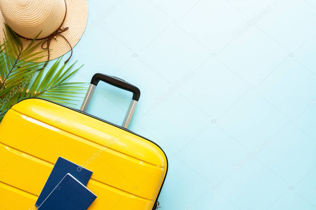 Suitcase, hat and flip flops on blue background. Happy Holidays, travel concept. Flat lay with space for text.