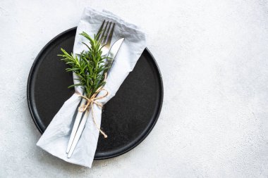 Beyaz taş masada siyah tabak ve çatal bıçak. Üst görünüm kopyalama alanı.