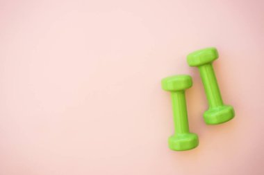 Pembe üzerine yeşil dambıllar. Kopyalama alanı olan düz resim.