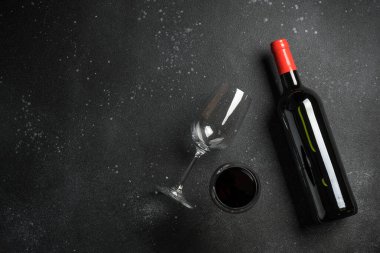 Kırmızı şarap. Şarap şişesi ve siyah arka planda bir bardak şarap. Kopyalama alanı olan üst görünüm.