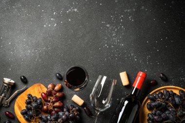 Kırmızı şarap siyah arka planda. Bir bardak şarap, şişe, çatal bıçak ve tirbuşon. Kopyalama alanı olan üst görünüm.