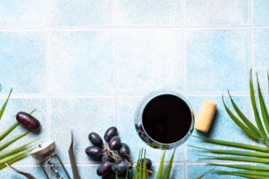 Mavi arka planda kırmızı şarap. Üzüm ve hurma yapraklı cam şarap. Kopyalama alanı olan düz resim.