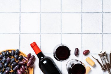 Beyaz arka planda kırmızı şarap. İki kadeh kırmızı şarap, şişe ve tirbuşon. Kopyalama alanı olan düz.