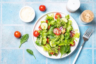 Beyaz tabakta taze yapraklı yeşil sebze salatası. Sağlıklı yemekler, diyet menüsü. Metin için boşluk olan üst görünüm.