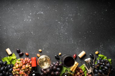 Şarap seti siyah arka planda. Beyaz ve kırmızı şarap, bir kadeh şarap, şişe ve taze krep. Kopyalama alanı olan üst görünüm.