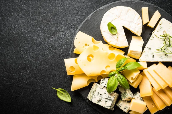 奶酪盘与工艺奶酪分类在板岩板上的黑色背景 顶部视图 — 图库照片