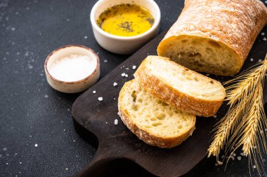 İtalyan Ciabatta ekmeği tahtanın üzerinde zeytin yağı ve buğday kulaklı..