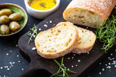 Tahtada ciabatta ekmeği, zeytin yağı, zeytin yağı ve siyah otlar. Akdeniz yemekleri.