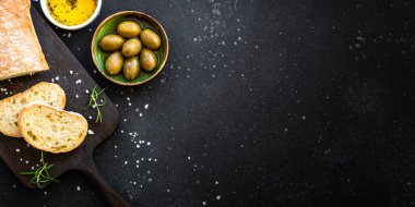 Tahtada ciabatta ekmeği, zeytin yağı, zeytin yağı ve siyah otlar. Kopyalama alanı olan üst görünüm.