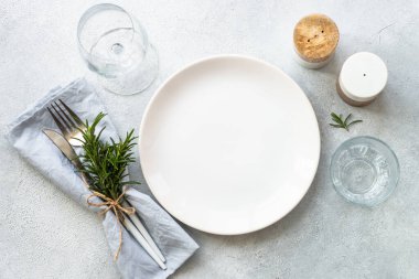 Beyaz tabak, karıştırıcı, şarap kadehi ve çatal bıçak takımı taş masada. Tablo ayarı, düz görünüm ve kopyalama alanı.