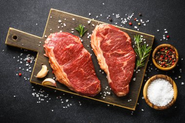 Beef steak with spices. Raw beef meat at black. Top view image.