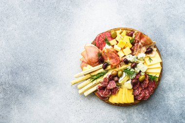 Antipasto tabağı. Peynir ve et - jamon, salam, ahşap tahtada taş zeminde zeytin. Üst görünüm.