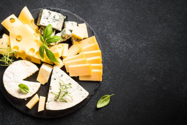 Siyah arkaplanda peynir çeşitleri var. Peynir çeşitleri. Kopyalama alanı olan üst görünüm.