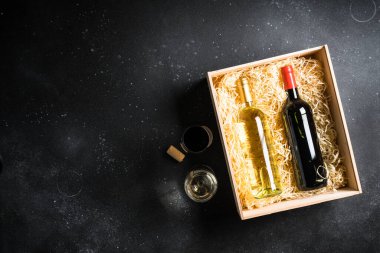 Siyah arka planda tahta kutuda kırmızı ve beyaz şarap. Kopyalama alanı olan üst görünüm.