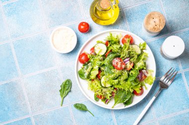 Beyaz tabakta taze yapraklı yeşil sebze salatası. Sağlıklı yemekler, diyet menüsü. Metin için boşluk olan üst görünüm.