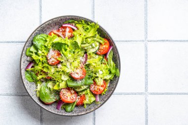 Taze yapraklı yeşil sebze salatası. Beyaz fayans arkaplanındaki üst görünüm.