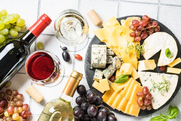 奶酪盘与工艺奶酪分类和葡萄酒杯白色瓷砖背景 顶部视图 — 图库照片