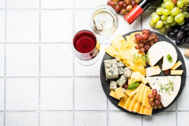 Beyaz karo arka planda tahta üzerinde peynir çeşitleri olan peynir tabağı. Üst görünüm.