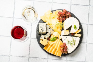 Peynir çeşnili peynir tabağı ve beyaz fayanslı şarap bardakları. Üst görünüm.