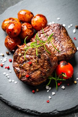 Barbekü yemeği. Siyah tahtada patates ve domatesli et bifteği. Kapat..