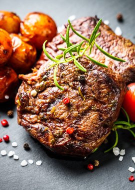 Barbekü yemeği. Siyah tahtada sebzeli et biftekleri ve otlar. Kapat..